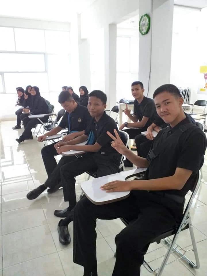 Peserta duduk di kelas dan tersenyum ke kamera